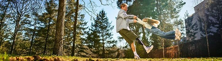 Vater spielt ausgelassen mit seinem Kind im Grünen an einem sonnigen Tag