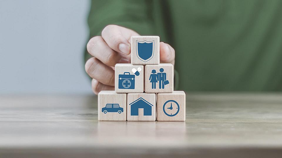 Holzklötze mit Symbolen im Zusammenhang mit Versicherungstipps. 