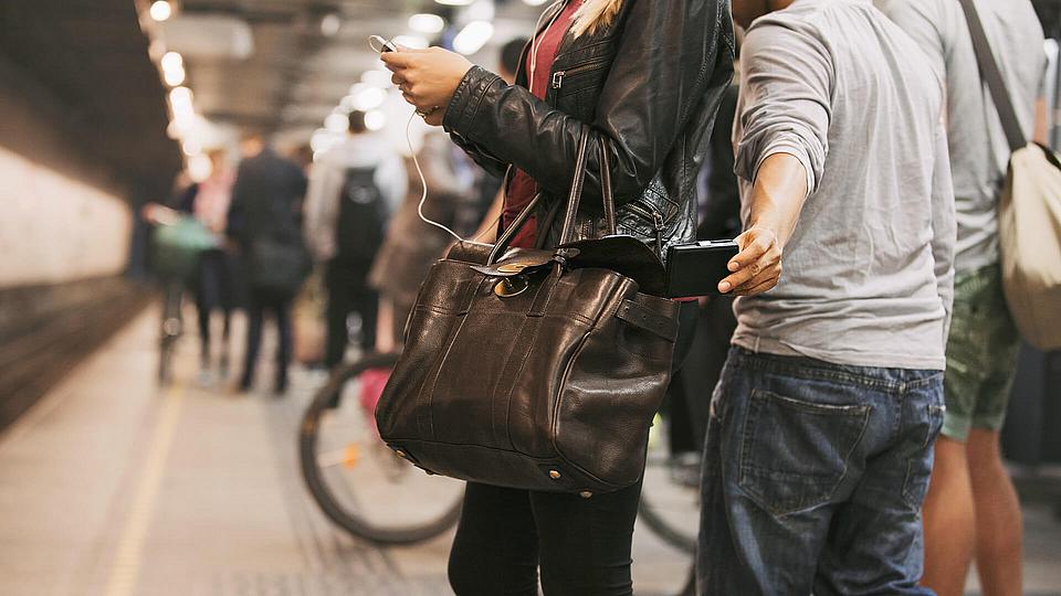 Ein Taschendieb zieht ein Handy aus der Tasche einer jungen Frau Ein Taschendieb zieht ein Handy aus der Tasche einer jungen Frau