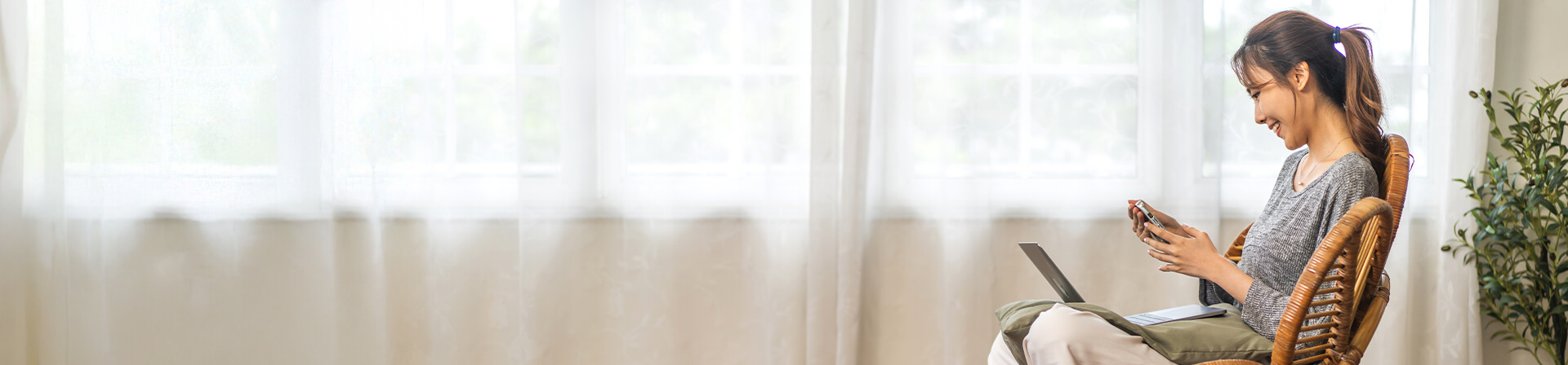 Eine Frau sitzt auf einem Stuhl und schaut lächelnd in ihr Smartphone. Eine Frau sitzt auf einem Stuhl und schaut lächelnd in ihr Smartphone.