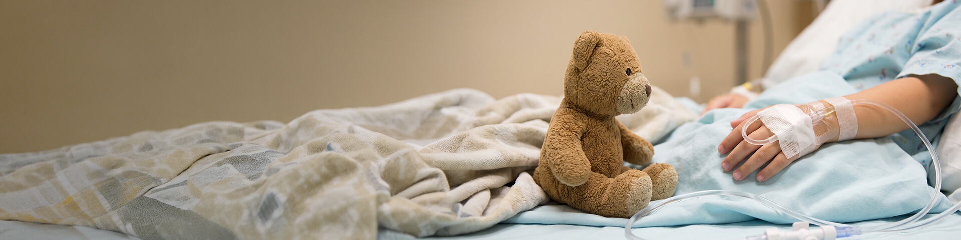 Kind liegt im Krankenhausbett mit Kuscheltier Kind liegt im Krankenhausbett mit Kuscheltier