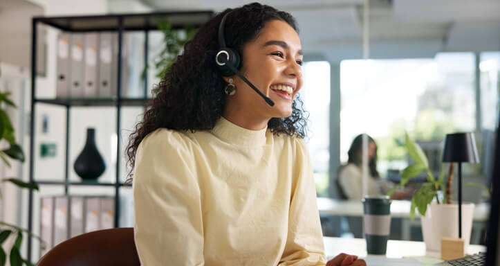 Frau mit Headset und gelbem Pullover in einem Büro Frau mit Headset und gelbem Pullover in einem Büro
