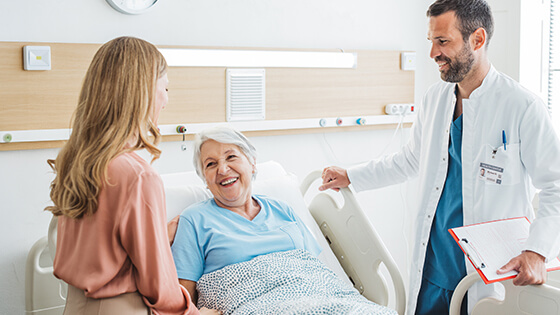 Patientin im Krankenhaus mit Besuch und einem Arzt