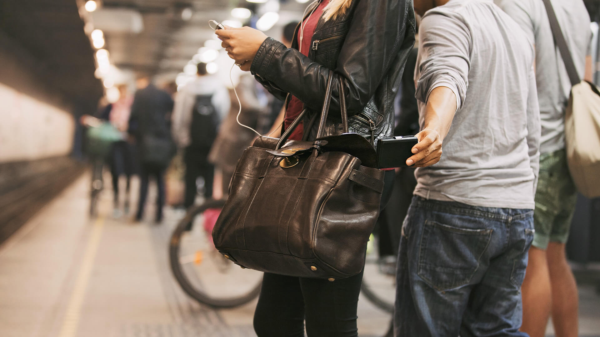 Ein Taschendieb zieht ein Handy aus der Tasche einer jungen Frau